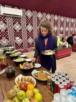 a woman holding a plate of food at a buffet at Wadi Rum Faris in Wadi Rum