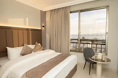 a bedroom with a bed and a table and a window at JAZEERAT QUBTAN in Aqaba