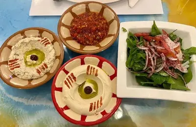 a table with three bowls of food and a salad at JAZEERAT QUBTAN in Aqaba