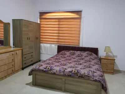 a bedroom with a bed and wooden cabinets and a window at Golden hotel in Jerash