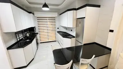 a kitchen with white cabinets and a black counter top at شقق عمو سامي بغرفة نوم 1 in Amman