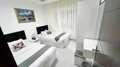 a white bedroom with two beds and a window at شقق عمو سامي بغرفتين نوم 2 in Amman