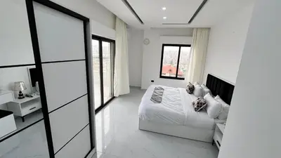 a white bedroom with a bed and a window at شقة رووف اطلاله رائعه عمو سامي 20 in Amman