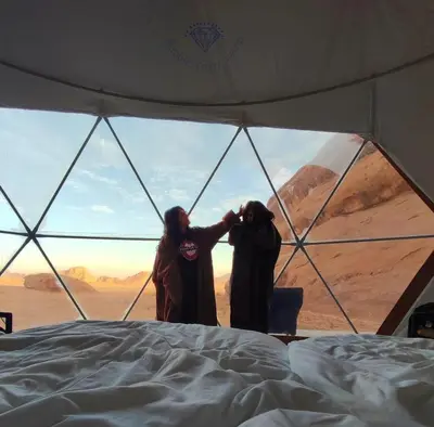 two people standing in a tent looking out at the desert at Bubble Emily camp in Wadi Rum