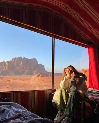 a woman sitting in a bus looking out the window at the desert at Moon shine camp in Wadi Rum