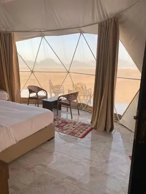 a bedroom with a bed and a view of the desert at Desert Elegance Luxury Bedouin Camp Panoramic View in Wadi Rum