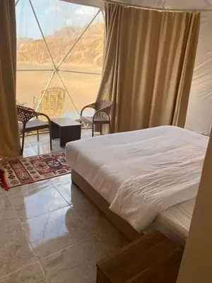 a bedroom with a bed and a view of the desert at Desert Elegance Luxury Bedouin Camp Panoramic View in Wadi Rum