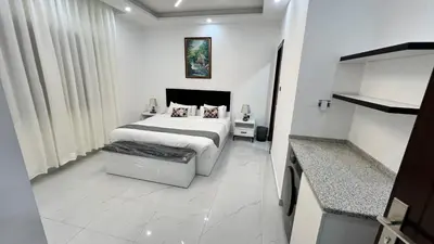 a white bedroom with a bed and a table at شقة بثلاث غرف نوم 3 عمو سامي in Amman