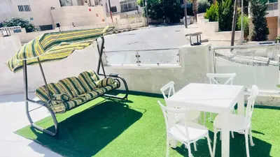 a chair and an umbrella and a table on a balcony at شقة بثلاث غرف نوم 3 عمو سامي in Amman