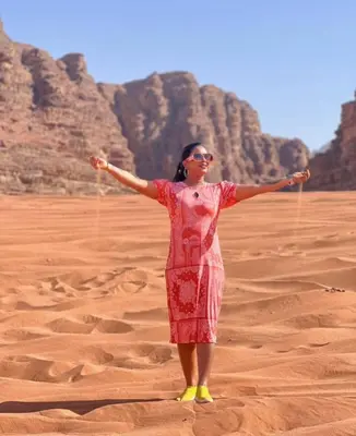 a woman standing in the desert with her arms outstretched at Romantic Moment Rum CAMP in Wadi Rum
