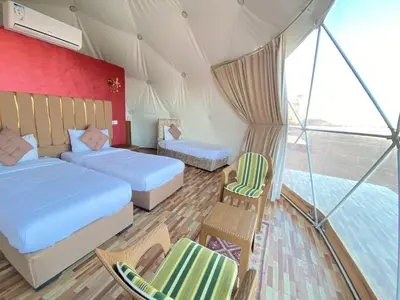 a room with two beds and chairs in a tent at Romantic Moment Rum CAMP in Wadi Rum