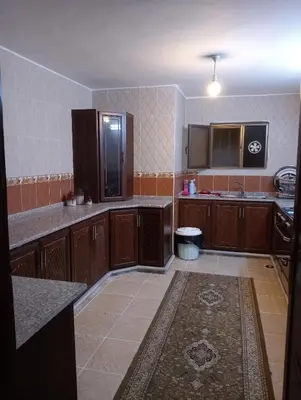 a large kitchen with wooden cabinets and a tile floor at Bait al salam in Um Qeis