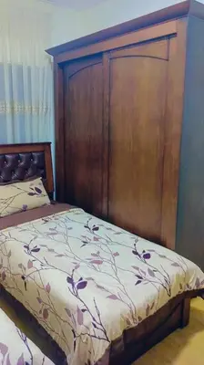 a bedroom with a bed with a large wooden headboard at شقة فاخرة واسعة في شارع المدينة المنورة in Umm Uthainah