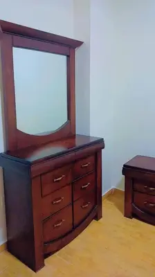 a wooden dresser with a mirror on top of it at شقة فاخرة واسعة في شارع المدينة المنورة in Umm Uthainah