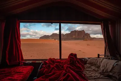 a bed in a room with a view of the desert at Wadirum sunset camp in Wadi Rum