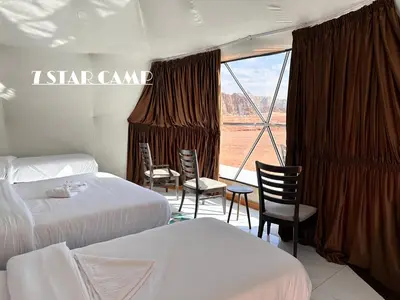 a hotel room with two beds and a large window at 7star camp in Wadi Rum