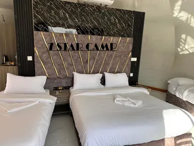 two beds in a hotel room with white sheets at 7star camp in Wadi Rum