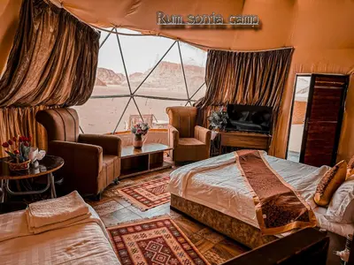 a bedroom with a bed and a view of the desert at sonia luxury camp in Wadi Rum