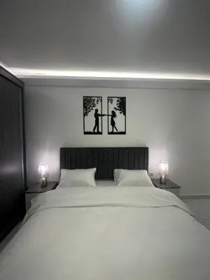 a bedroom with a large bed with two pictures on the wall at Cozy and Tranquil Rooftop Near Al Services 23 in Amman
