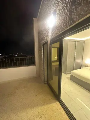 a bedroom with a bed and a balcony at night at Cozy and Tranquil Rooftop Near Al Services 23 in Amman