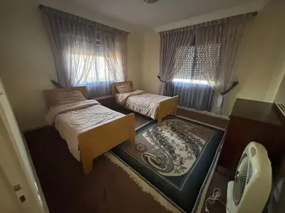 a small bedroom with two beds and a window at Zahrat AL-Mada'in apartment in Irbid