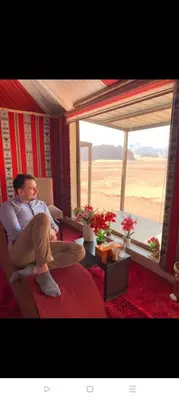 a man sitting in a chair in a room with a window at Rum Honeymoon Camp in Wadi Rum