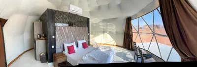 a bedroom with a bed with a large window at Rum Green Camp in Wadi Rum