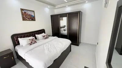 a bedroom with a bed with white sheets and pillows at شقة بثلاث غرف نوم الجاردنز عمو سامي in Amman