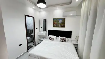 a white bedroom with a bed and a mirror at شقة بثلاث غرف نوم الجاردنز عمو سامي in Amman