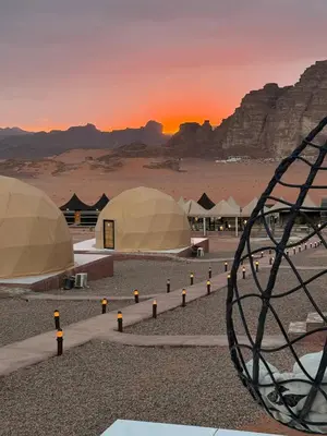 a group of tents in the desert with the sunset at Desert Oasis Lodge in Wadi Rum in Disah