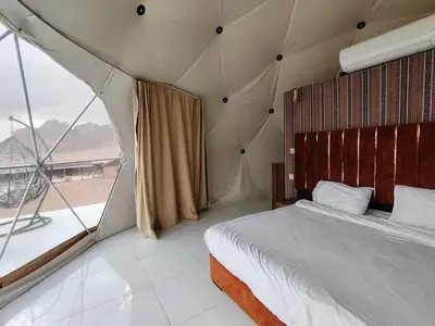 a bedroom with a bed and a large window at Desert Oasis Lodge in Wadi Rum in Disah