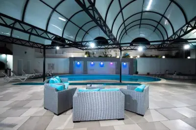 a large swimming pool with chairs in a building at Gerasa Breeze resort in Rujm al Miḑmār