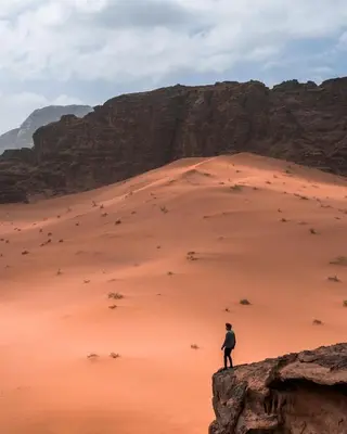 a person standing on a rock in a desert at desert Hawk in Wadi Rum
