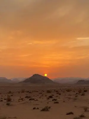 a sunset in the desert with a mountain in the background at Salem Wadi Rum Road in Wadi Rum