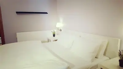 a white bed with white sheets and pillows at Two Bedroom Shmeisani Apartment in Amman