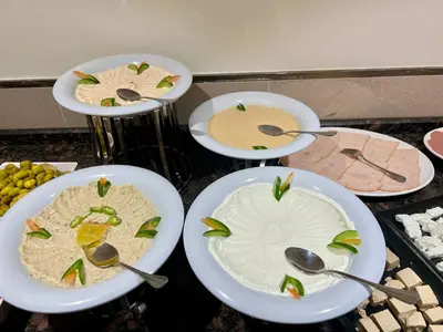 four plates of food on a counter with spoons at Saraya Abdeen Hotel in Aqaba