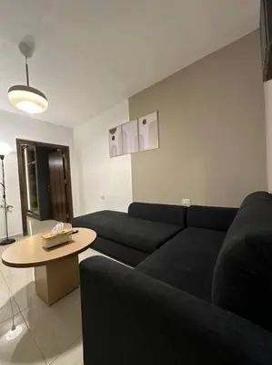 a living room with a black couch and a table at Stylish Luxe Apartment F/R 0002 in Amman