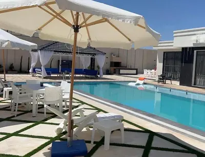 a pool with a table and chairs and an umbrella at Tixos Farm in Irbid