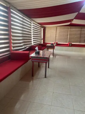 a waiting room with red couches and a table at Omar Camp Wadi Rum in Disah