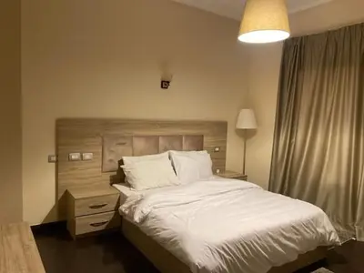 a bedroom with a large white bed with a wooden headboard at Holy land in Amman