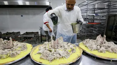 a man in a kitchen preparing food on two pizzas at look house in Amman