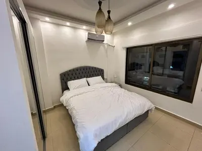 a bedroom with a bed with white sheets and a window at Luxury Hotel apartment in Amman