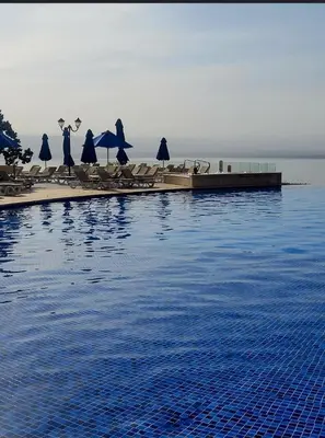 a pool with chairs and umbrellas next to the water at Samarah Resort D32 in Sowayma