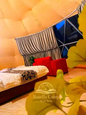 a bedroom with a bed with red pillows at Rosella Camp Wadi Rum in Wadi Rum