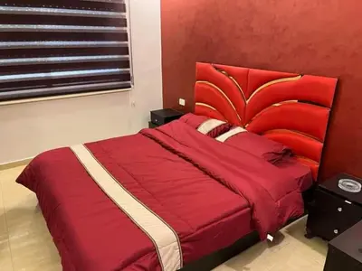 a red bed with a red headboard in a bedroom at Nerman home in ‘Awjān ash Shamālī