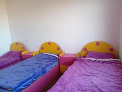 two beds in a room with purple and yellow at Nerman home in ‘Awjān ash Shamālī