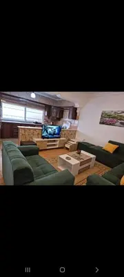 a living room with green couches and a flat screen tv at Nerman home in ‘Awjān ash Shamālī