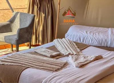 a room with a bed and a chair and towels at Daria Luxury Camp in Wadi Rum
