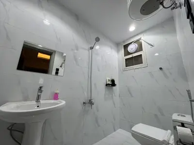 a white bathroom with a toilet and a sink at GOJORDAN INN in Irbid