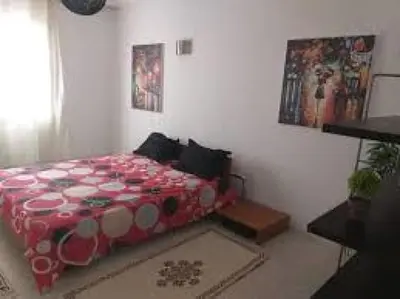 a bedroom with a bed with a red and white comforter at 360 INNn in Irbid